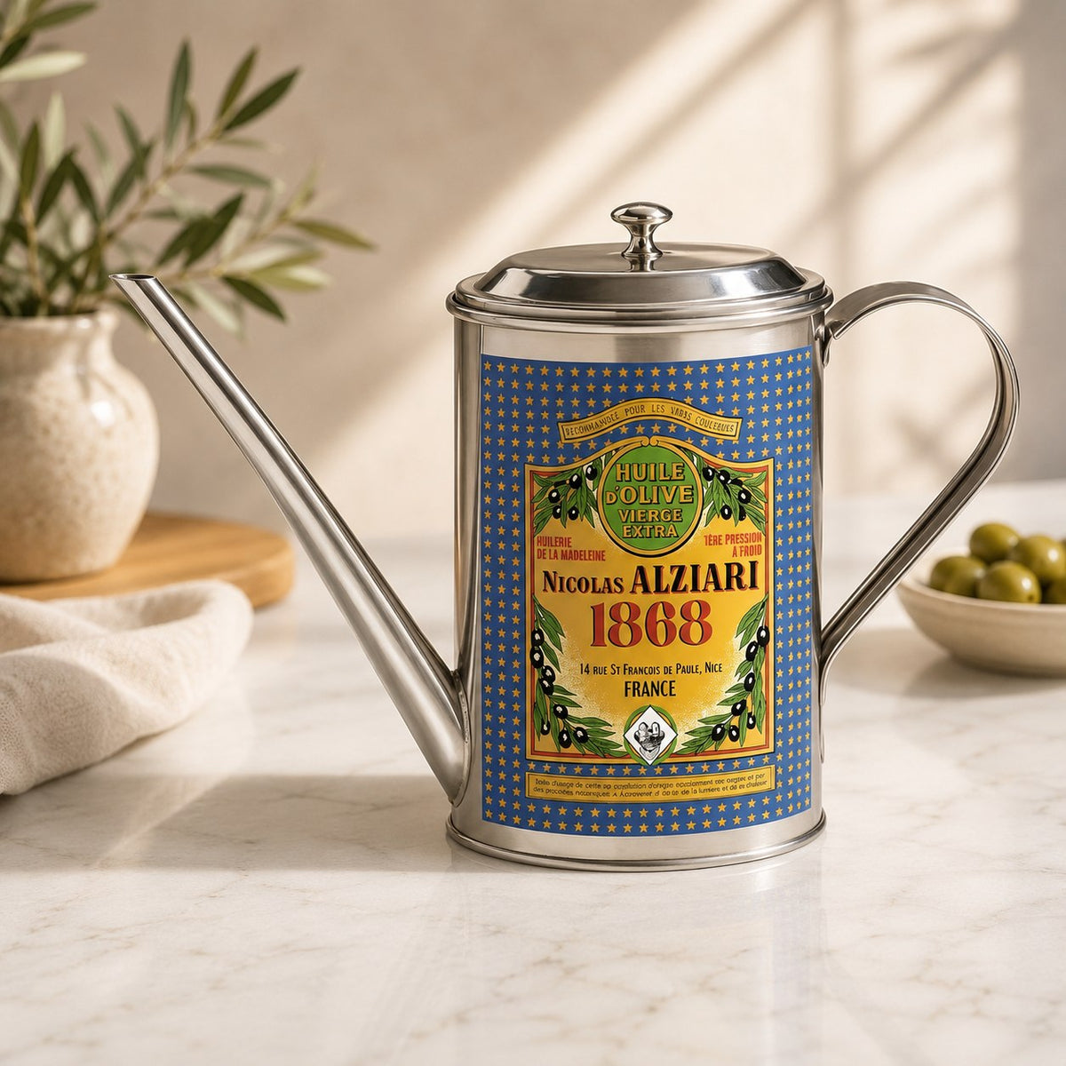 Huilier Nicolas Alziari sur un plan de travail en marbre, avec des olives