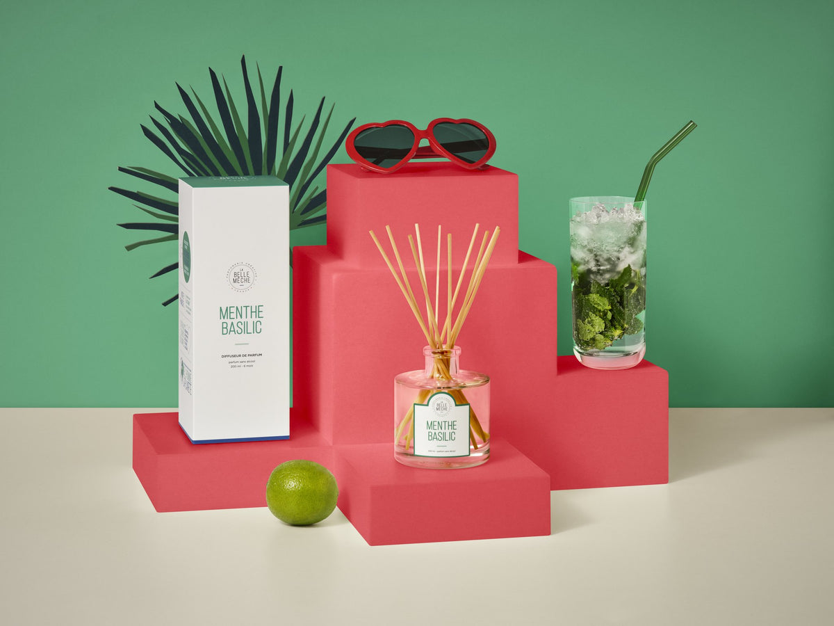 Diffuseur à bâtonnets Menthe Basilic de La Belle Mèche à côté d’un mojito