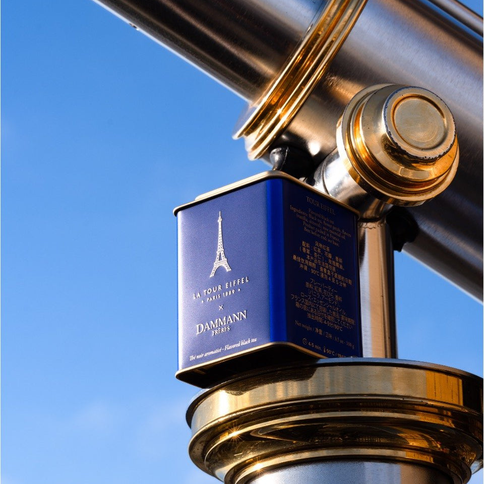 Blue Dammann Frères La Tour Eiffel tea tin on a brass telescope against a blue sky