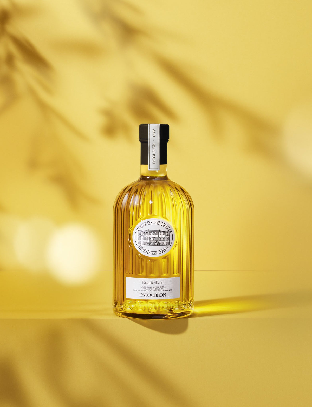 Huile d’olive monovariétale Bouteillan du Château d’Estoublon, mise en scène sur fond jaune