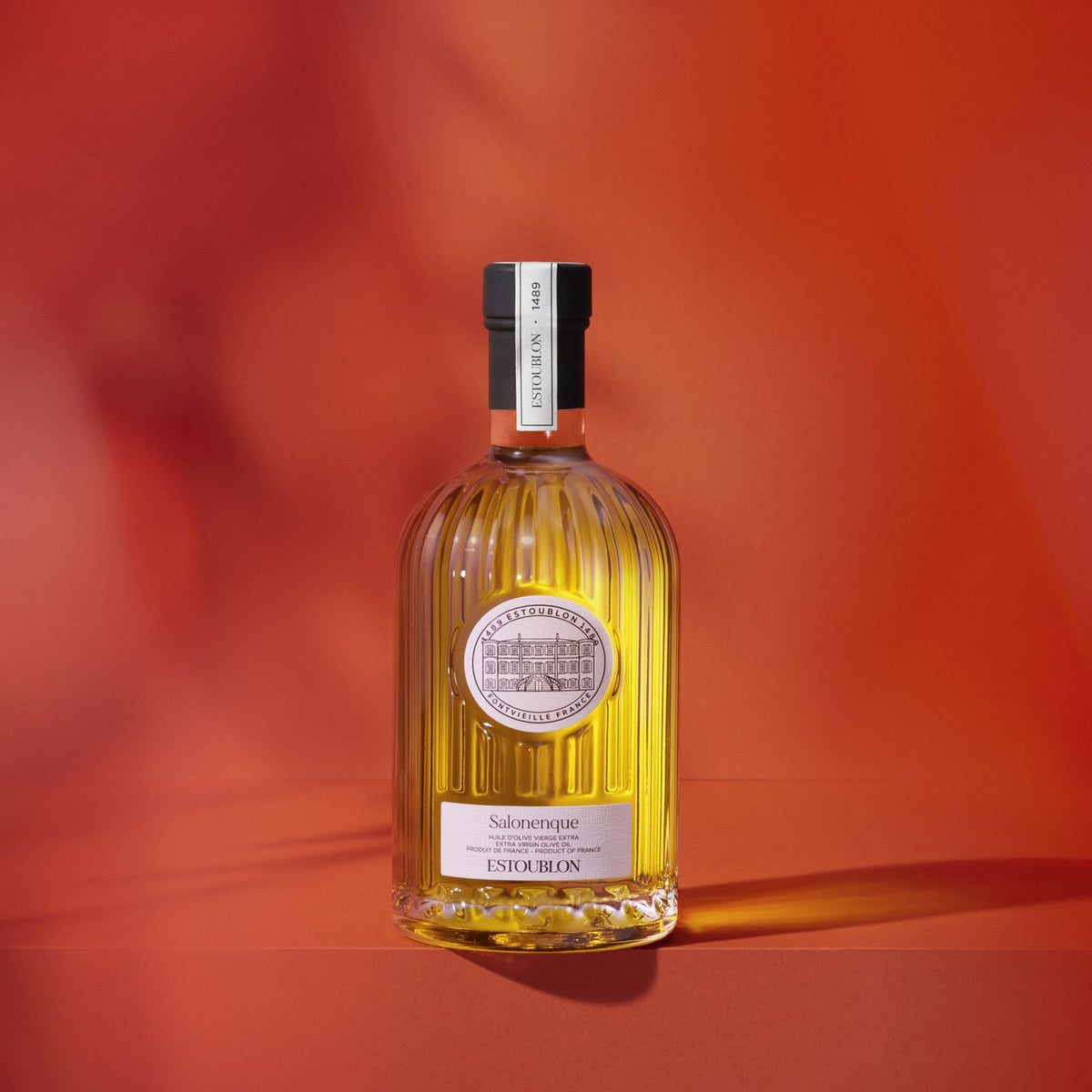 Salonenque single-variety olive oil by Château d'Estoublon, styled on a red background