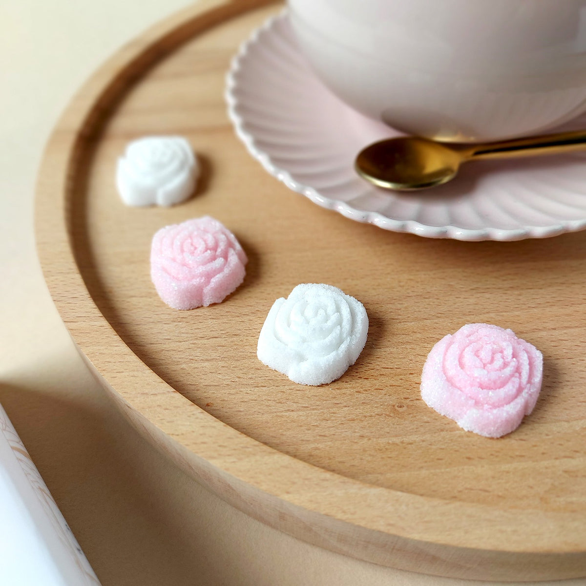 Sucres Canasuc roses et blancs en forme de rose sur un plateau en bois