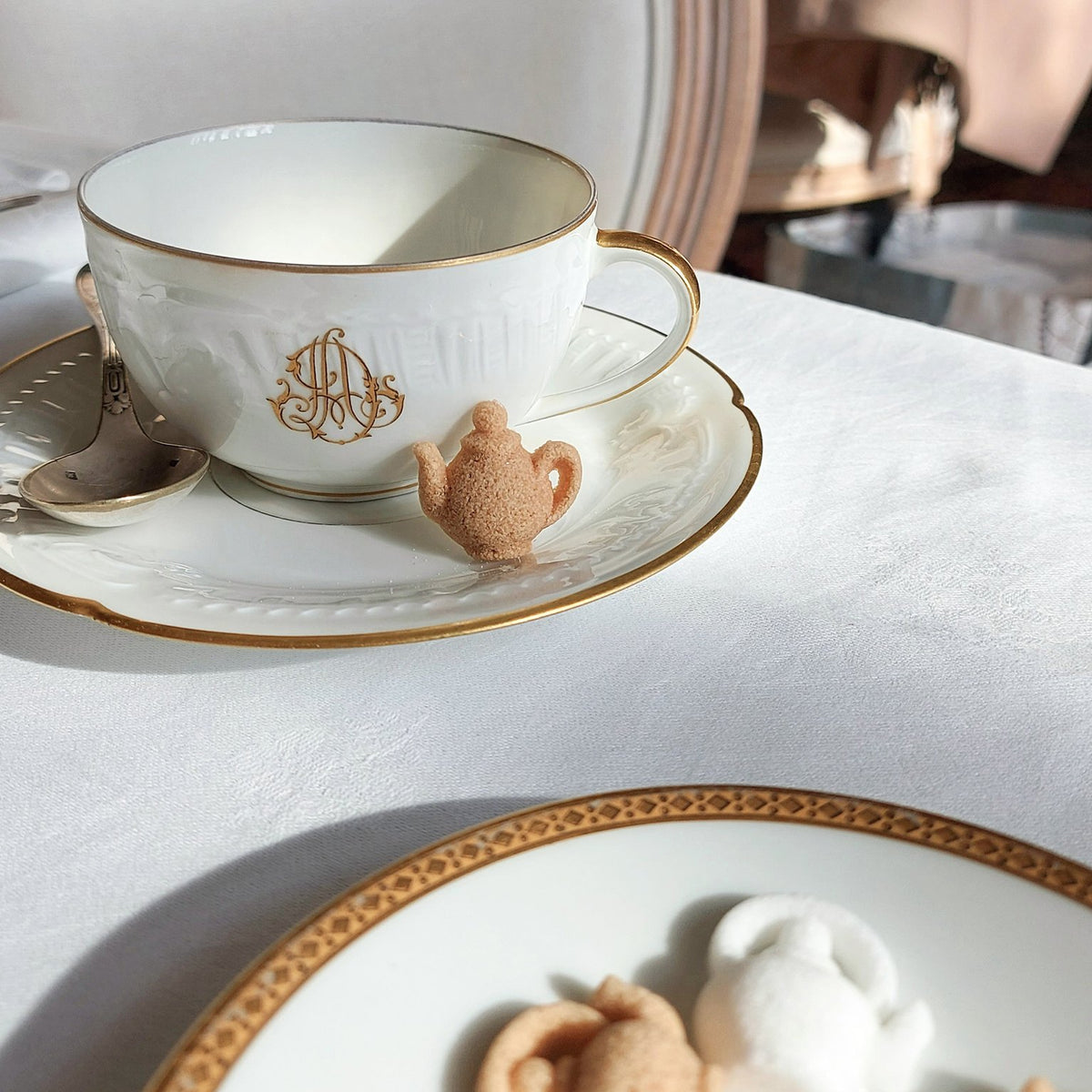 Sucres Canasuc en forme de théière à côté d’une tasse à thé dorée