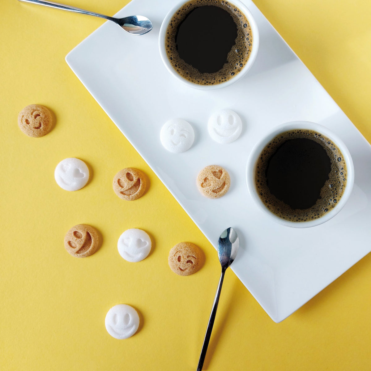 Sucres Smiley Canasuc avec deux tasses de café sur une table jaune