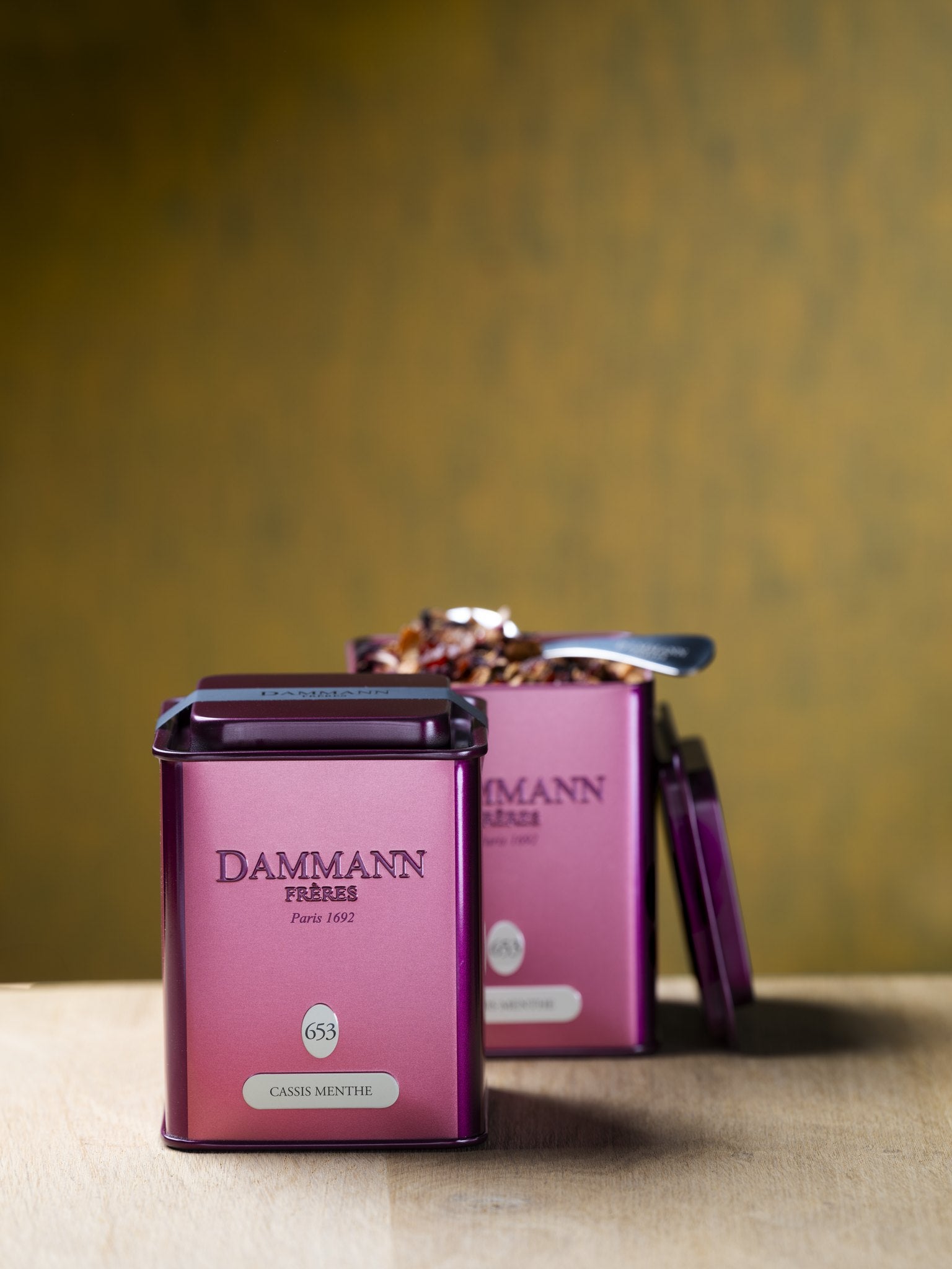 Dammann Frères Carcadet Cassis Menthe canisters on a wooden table