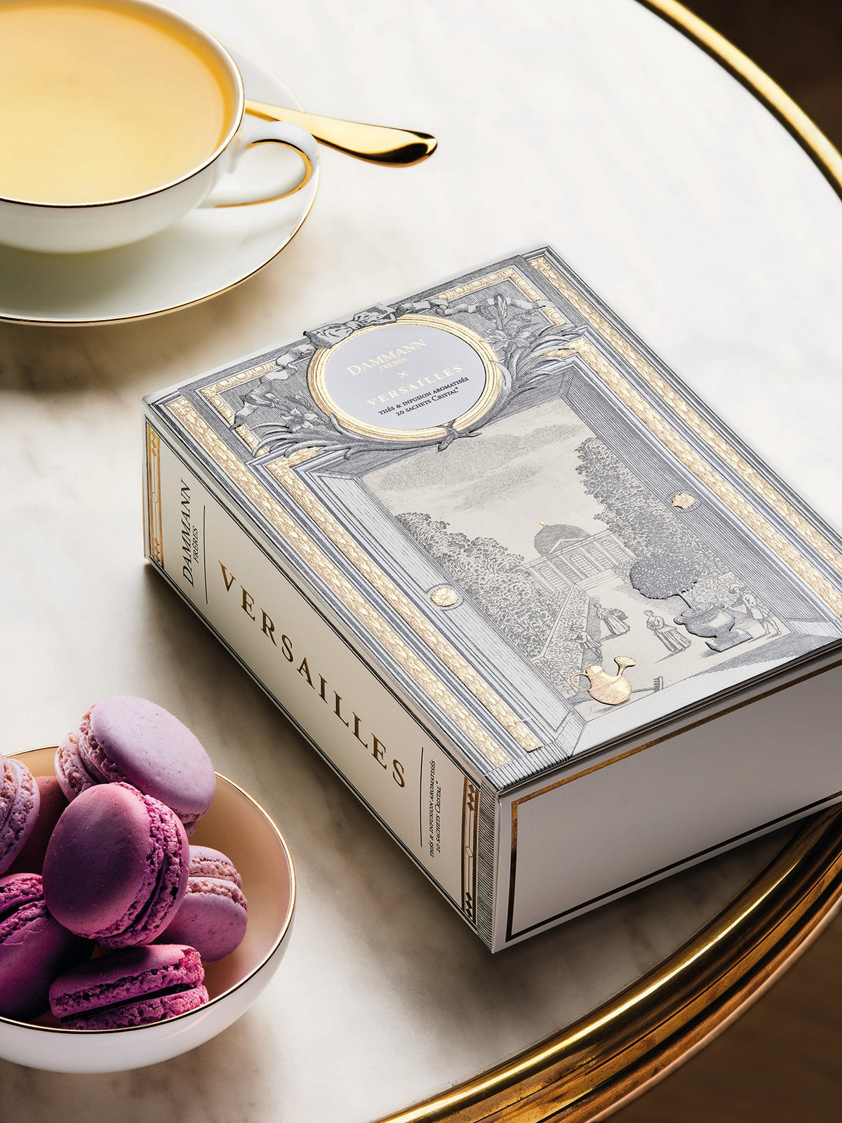 Coffret Versailles de Dammann Frères avec des macarons et une tasse de thé
