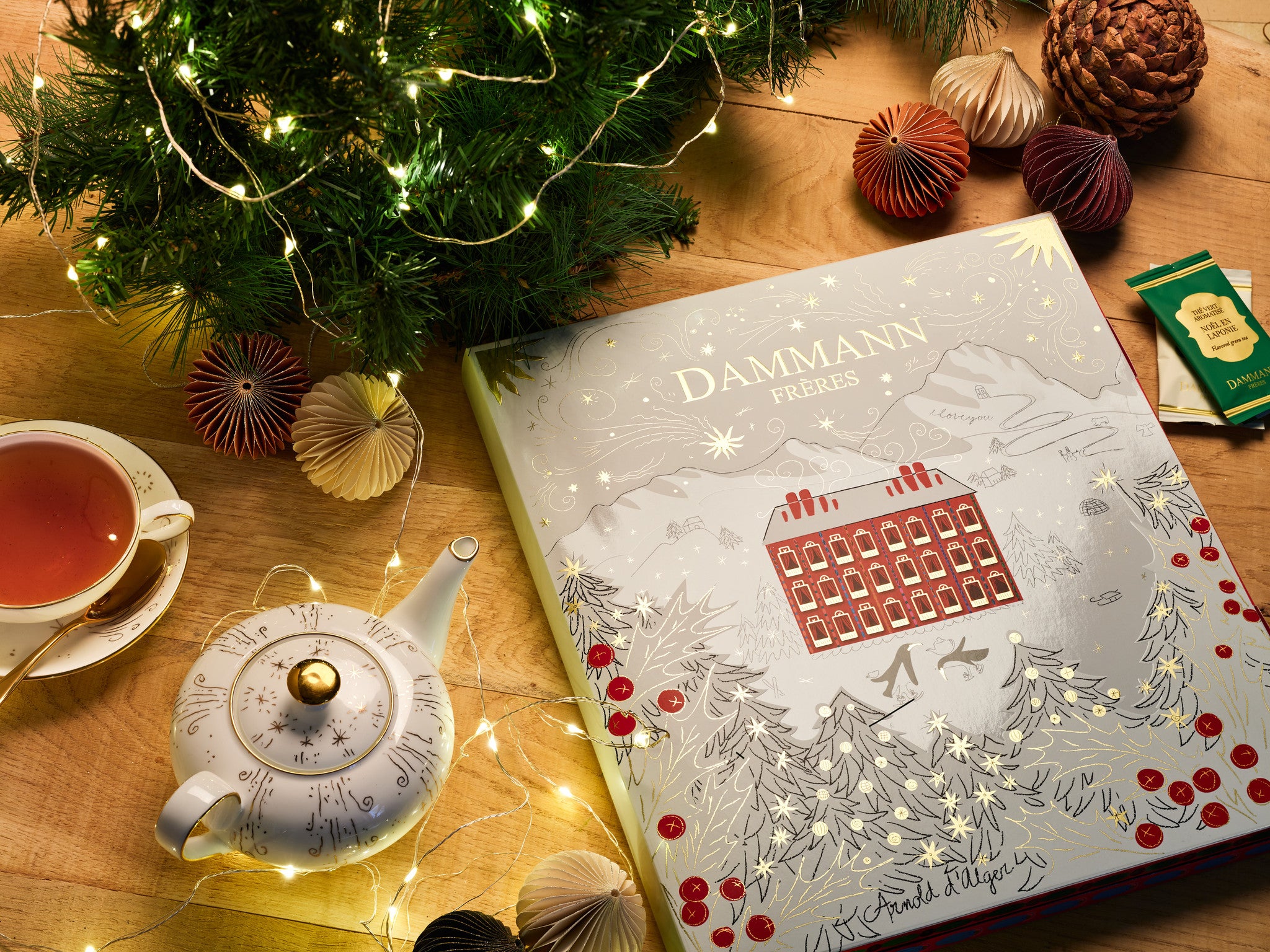 Advent Calendar by Dammann Frères on a wooden table with a teapot, a cup of tea and Christmas decorations