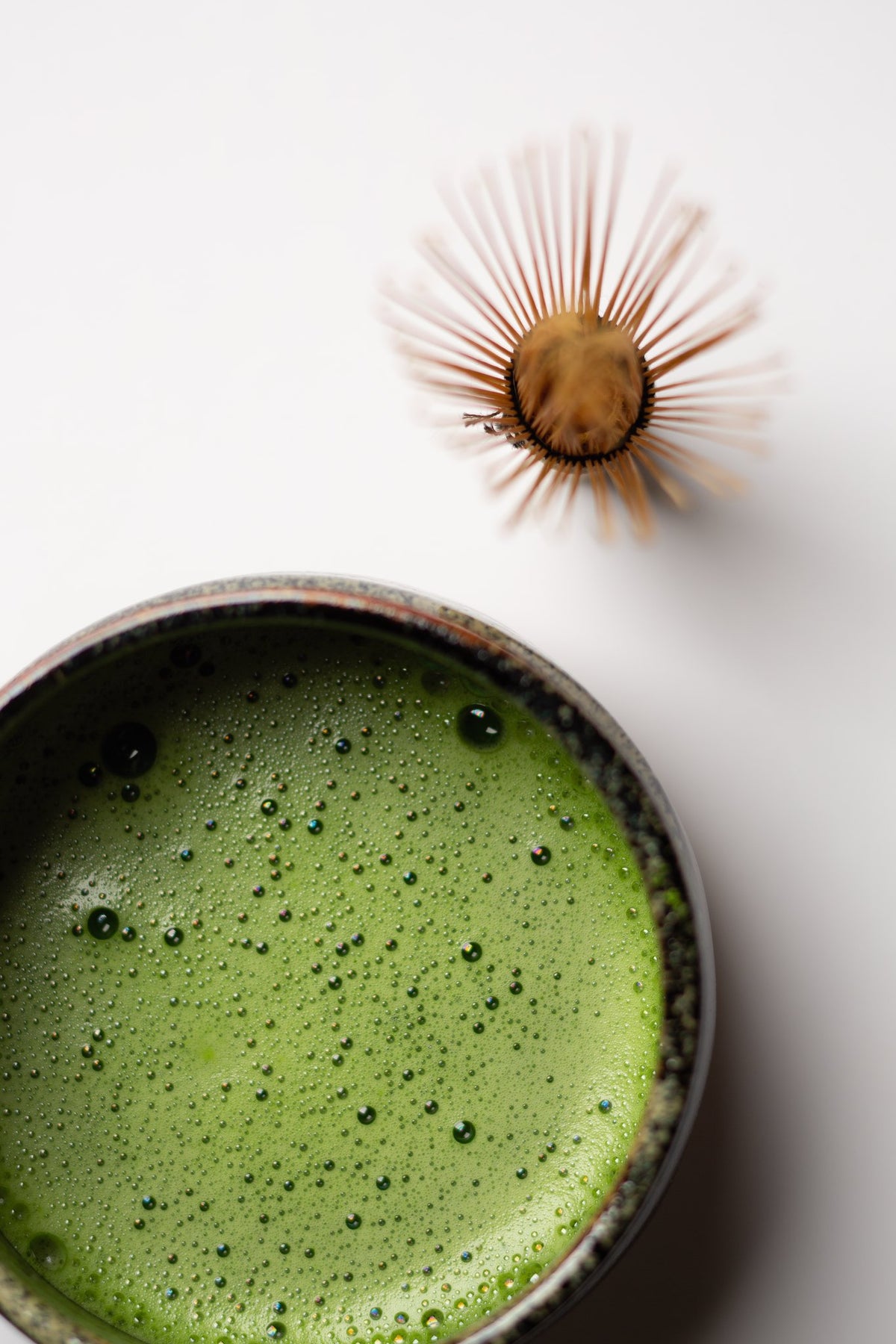 Bamboo chasen whisk above a bowl of frothy matcha